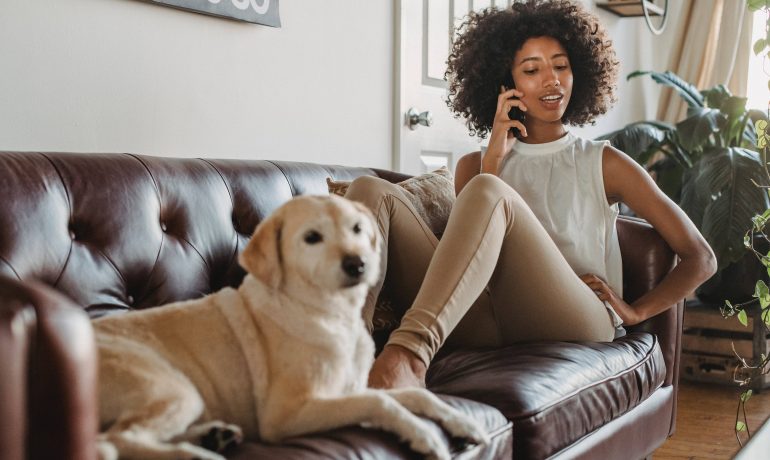 happy lady on sofa talking on telephone waiting on hold